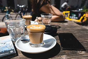 Flat white coffee on wooden table at outdoor cafe