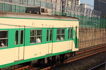 Green and cream commuter train on urban tracks in South Korea