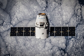 SpaceX Dragon spacecraft orbiting Earth above clouds