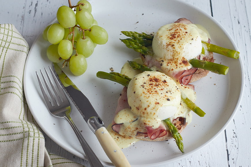 Eggs Benedict with Asparagus and Grapes on White Plate