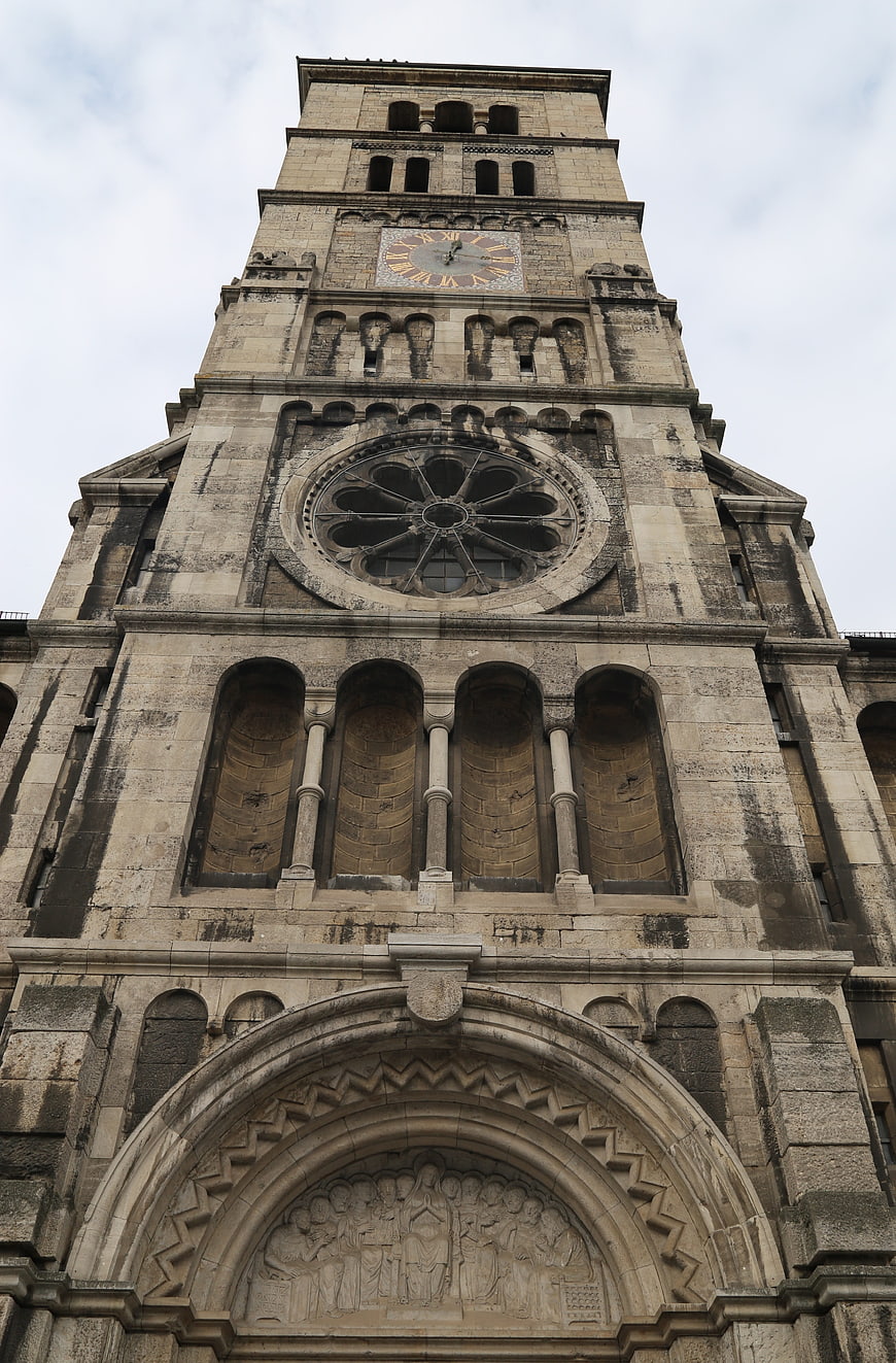 Low angle view of historic stone church tower with clock and rose window