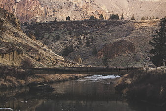Wooden bridge crossing river in rugged canyon landscape