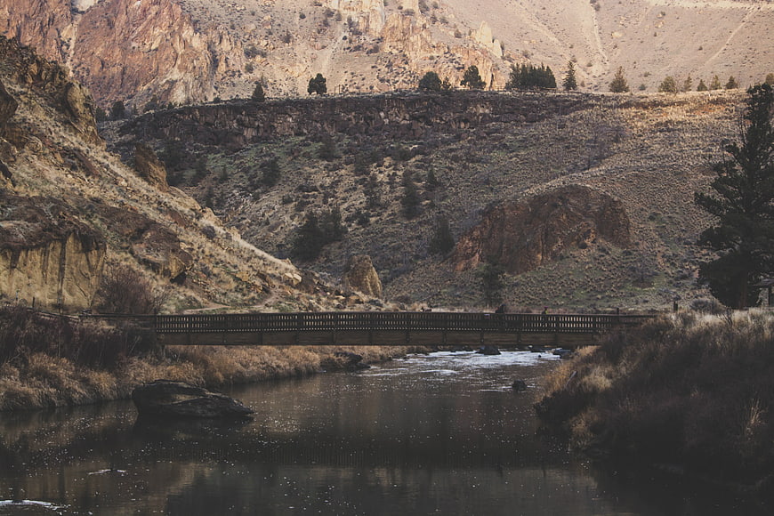 Wooden bridge crossing river in rugged canyon landscape