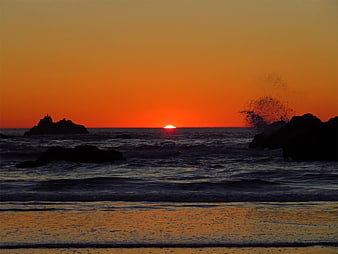 Dramatic Orange Sunset Over Ocean with Silhouetted Rocks