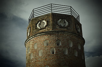 Old brick lighthouse tower against dramatic cloudy sky