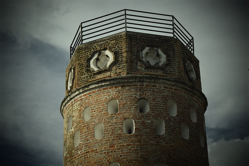 Old brick lighthouse tower against dramatic cloudy sky