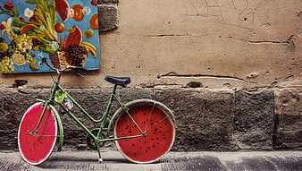 Green bicycle with watermelon wheels parked against a textured wall