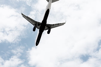 Low angle view of airplane flying through cloudy blue sky