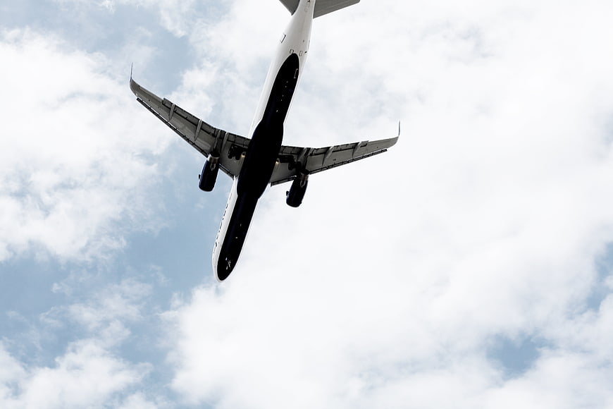 Low angle view of airplane flying through cloudy blue sky