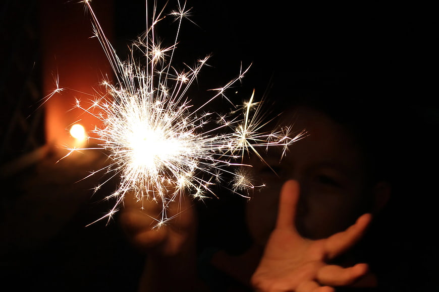 Child Holding Sparkler at Night with Peace Sign