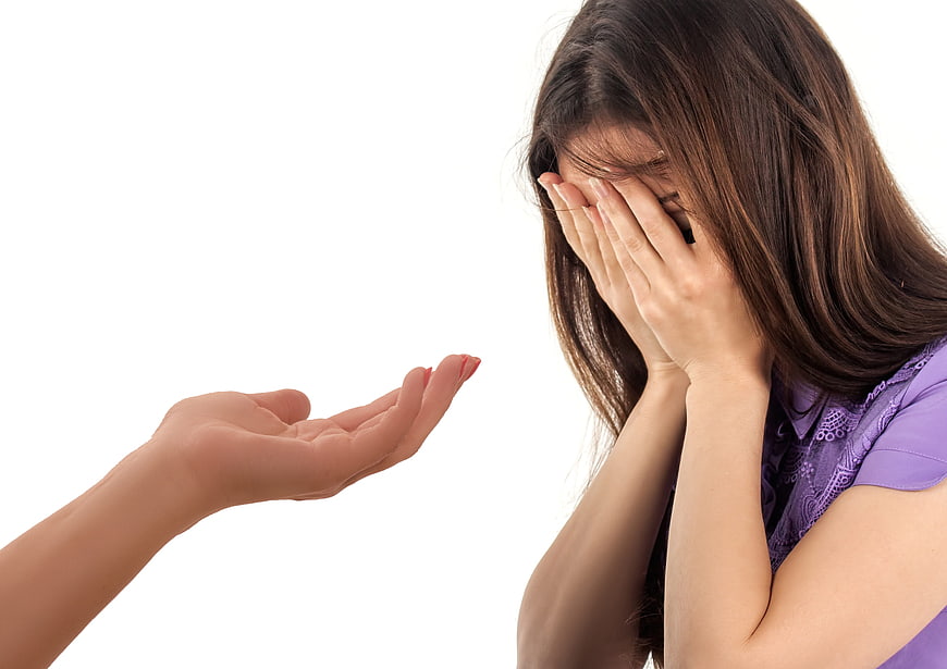 Sad woman covering face while receiving a helping hand