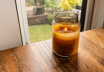 Lit Amber Candle in Glass Jar on Wooden Table