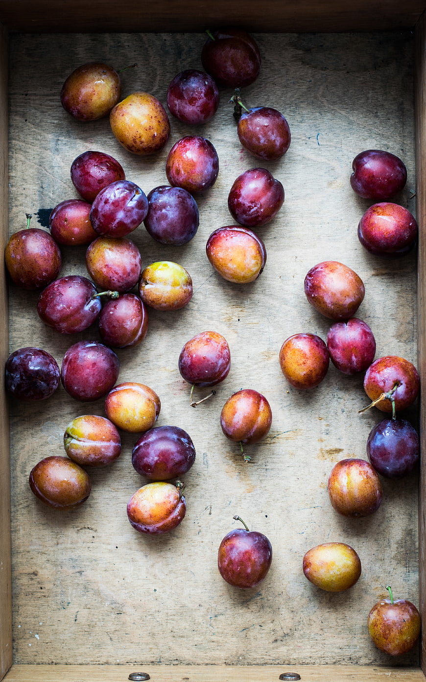 Fresh Plums Scattered in a Rustic Wooden Crate