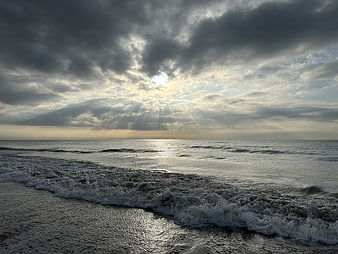 Dramatic Sun Rays Breaking Through Stormy Clouds Over Ocean Waves