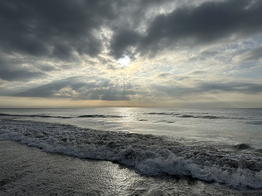 Dramatic Sun Rays Breaking Through Stormy Clouds Over Ocean Waves