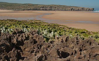 Rugged coastal landscape with mossy rocks and sandy beach
