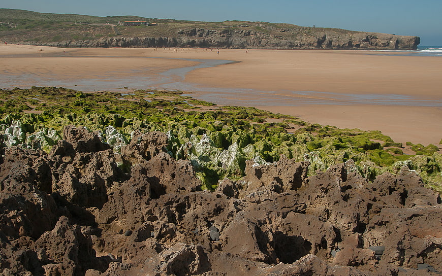Rugged coastal landscape with mossy rocks and sandy beach