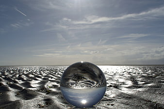 Crystal Ball on Sandy Beach with Ocean Reflection