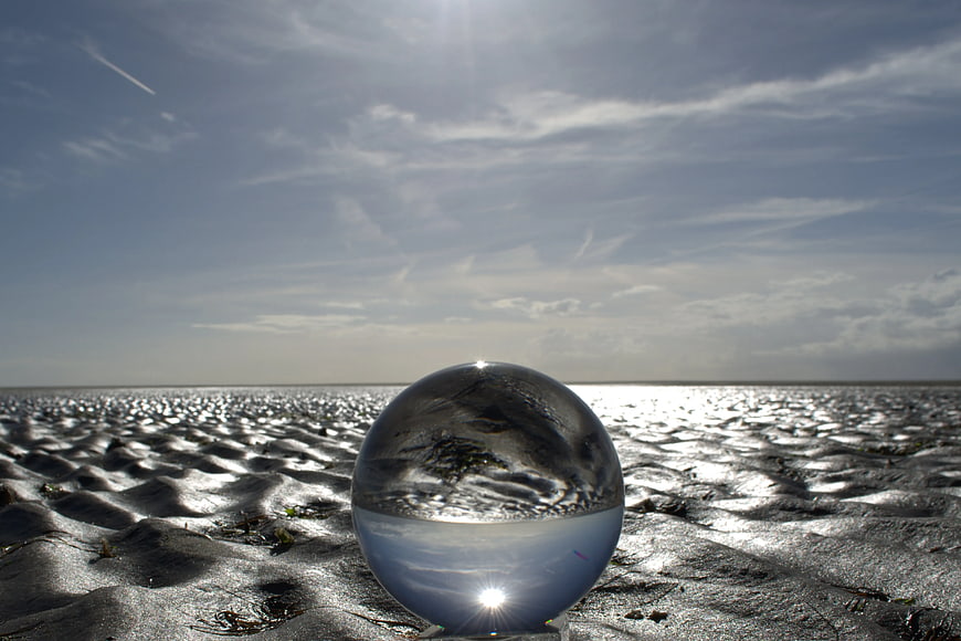 Crystal Ball on Sandy Beach with Ocean Reflection