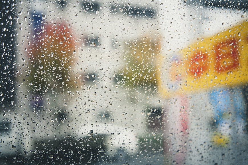 Raindrops on glass window with blurred city background
