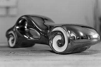 Shiny black and white streamlined car statuette on wood