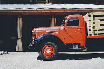 Vintage Orange Truck Parked in Front of Wooden Barn