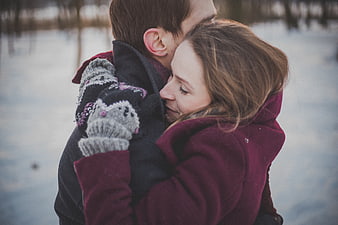 Couple Hugging in Winter Snow with Knitted Mittens