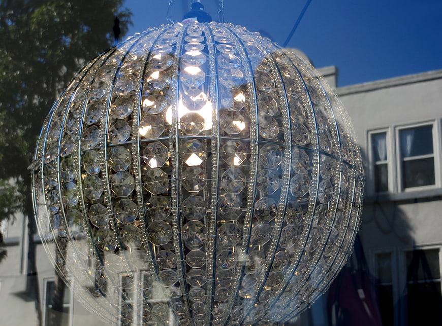Crystal sphere hanging in shop window against blue sky