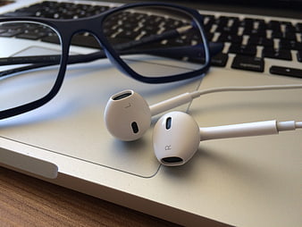 White Wired Earbuds and Glasses on Laptop Keyboard