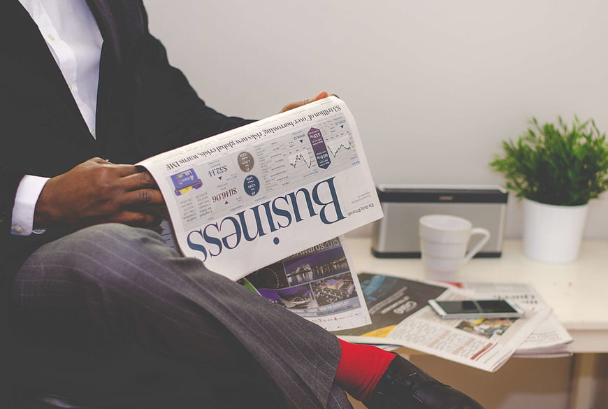 Businessman Reading Financial Newspaper In Modern Office