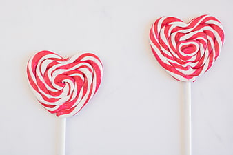 Two Heart-Shaped Pink and White Swirl Lollipops on White Background