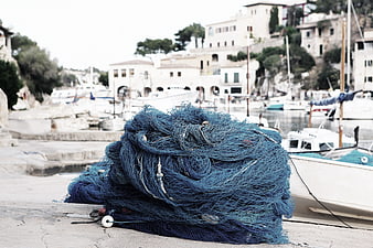 Blue fishing net pile on harbor dock with boats