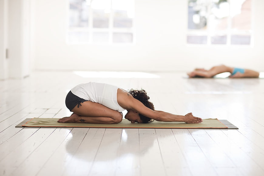 Woman in Child's Pose Yoga Stretch in Bright Studio