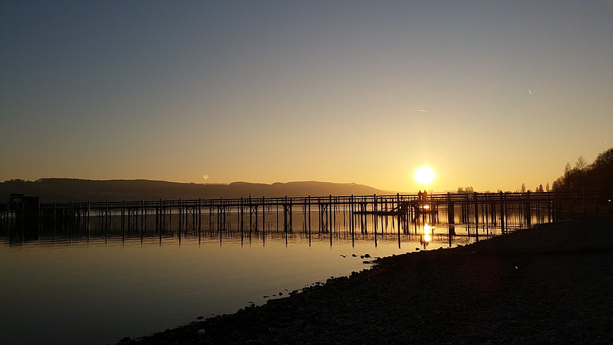 Sunset over Lake Constance with Silhouetted Pier and Mountains
