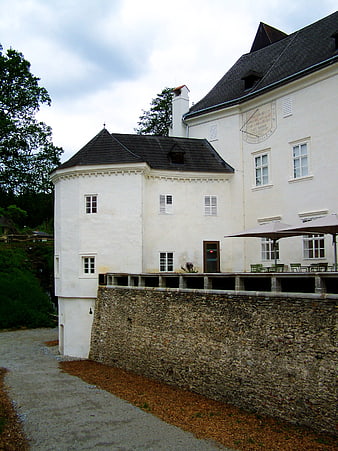 White historic castle building with stone wall and patio