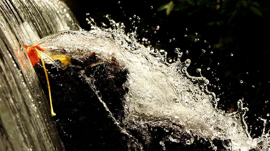 Dynamic Water Splash from Wooden Spout with Red Flower