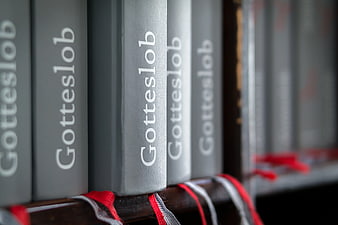 Close-up of Gotteslob hymnals on a wooden shelf