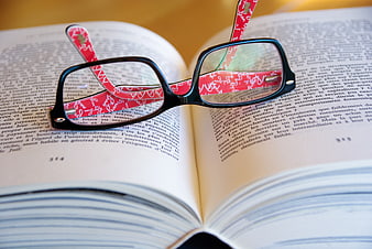 Black Eyeglasses with Red Straps on Open Book