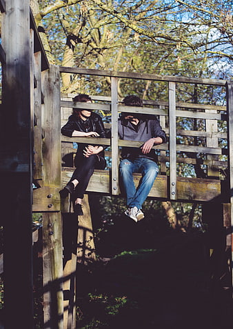 Couple sitting on wooden bridge in forest