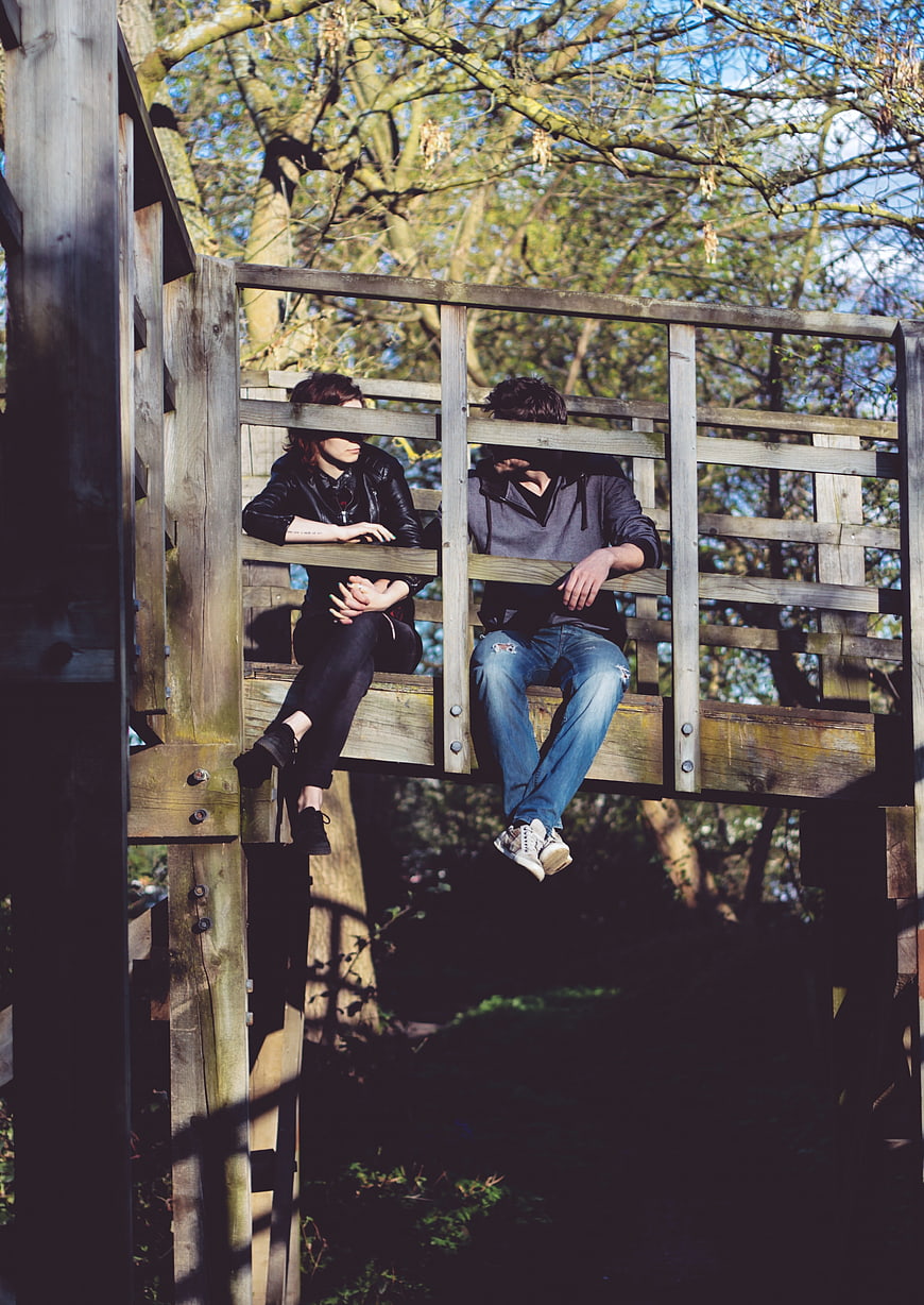 Couple sitting on wooden bridge in forest