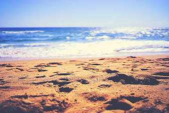Close-up of sandy beach with blurred ocean waves background