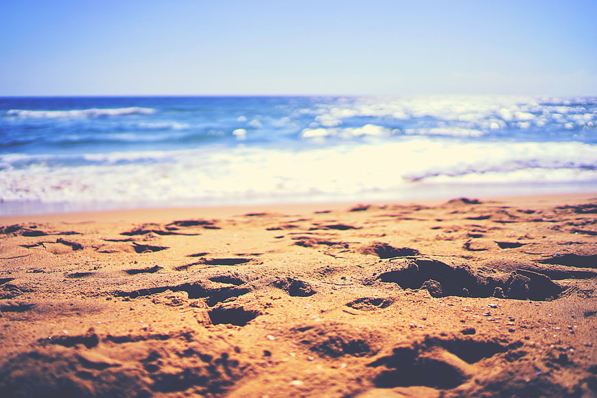 Close-up of sandy beach with blurred ocean waves background