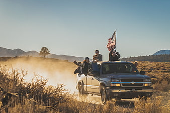 Group of friends riding in pickup truck with American flag