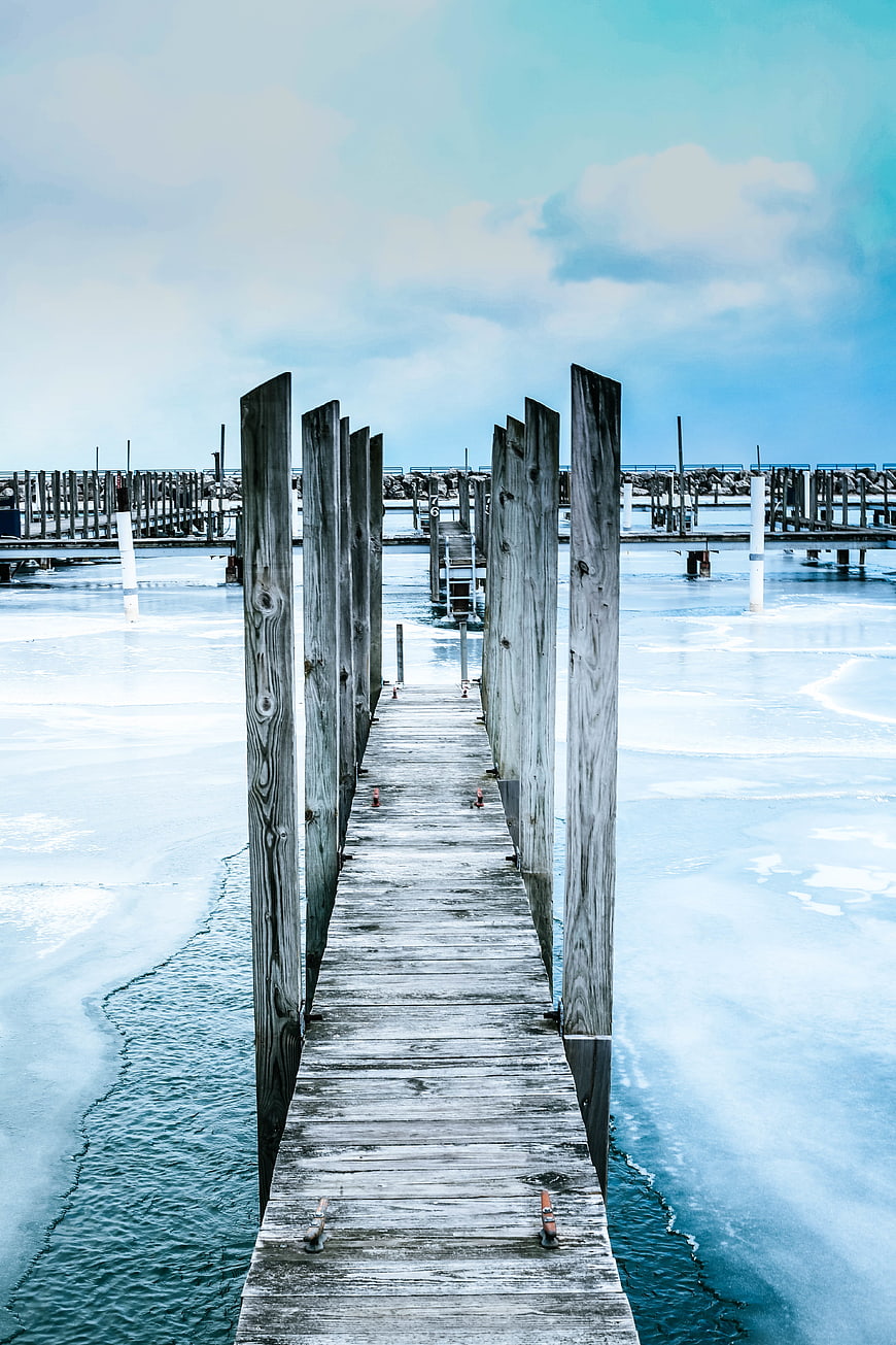Wooden pier extending into frozen icy water