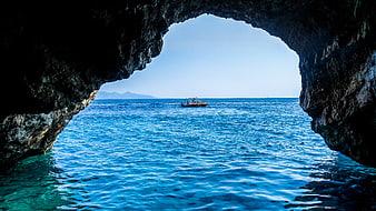 View of a boat on the ocean from inside a sea cave