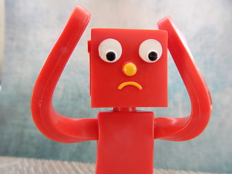 Red toy figurine with sad expression and hands on head