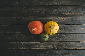 Three colorful pumpkins on dark rustic wooden background