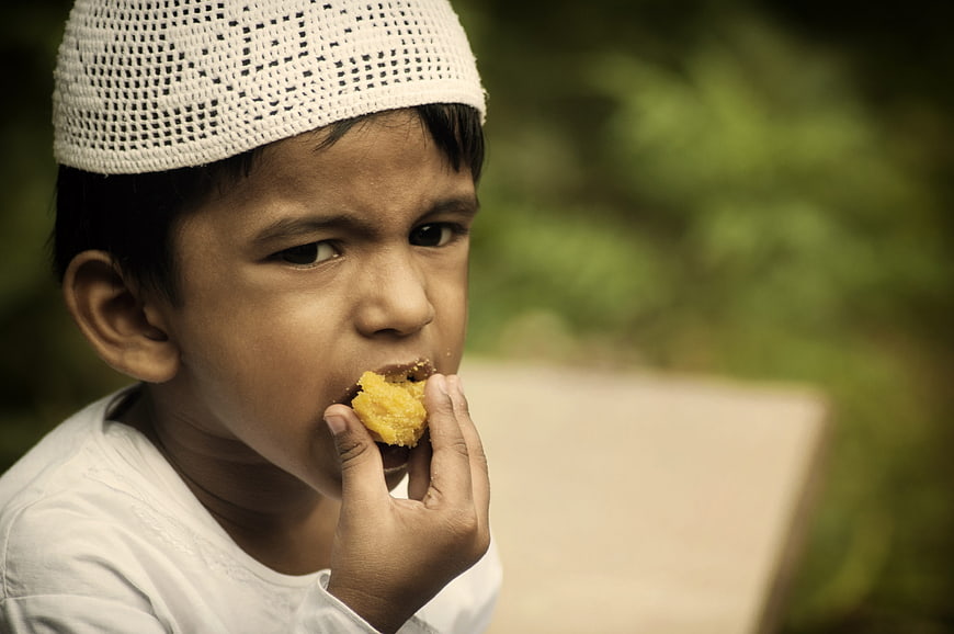 Young Muslim Boy Eating Sweet Ladoo Treat