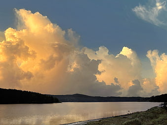 Dramatic golden clouds over calm lake at sunset