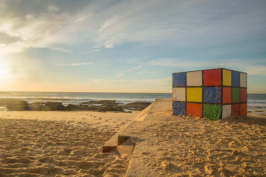 Giant Rubik's Cube Sculpture on Sandy Beach at Golden Hour